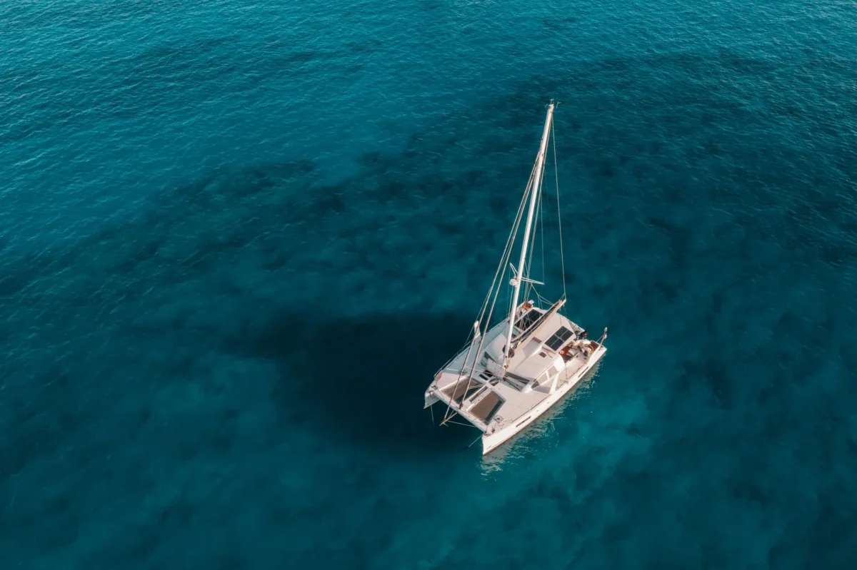Aerial view of a cruising catamaran with two hulls anchored in clear blue water