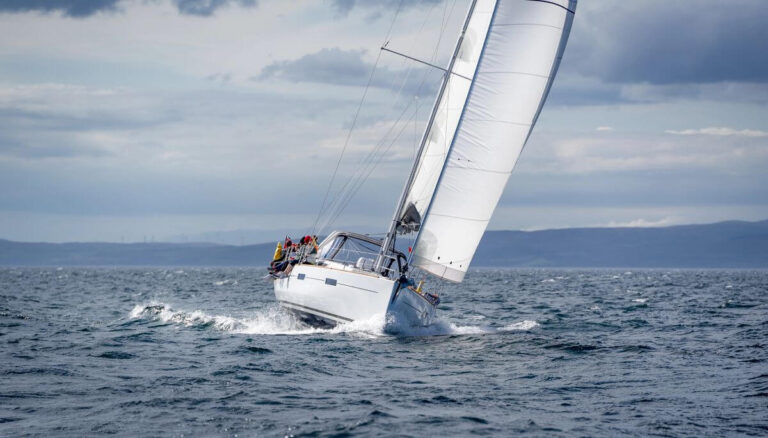 Sailing yacht heeling in choppy coastal waters under cloudy skies in Scotland